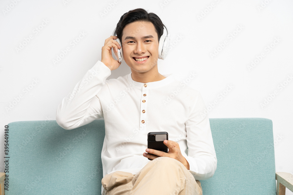 亚洲商人戴着无线耳机在智能手机上看视频