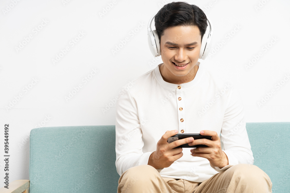 亚洲商人戴着无线耳机在手机上玩游戏