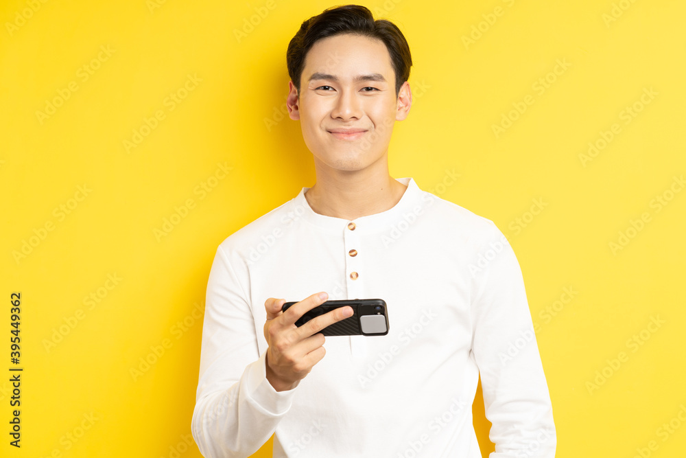 亚洲商人拿着手机在黄色背景下看电影