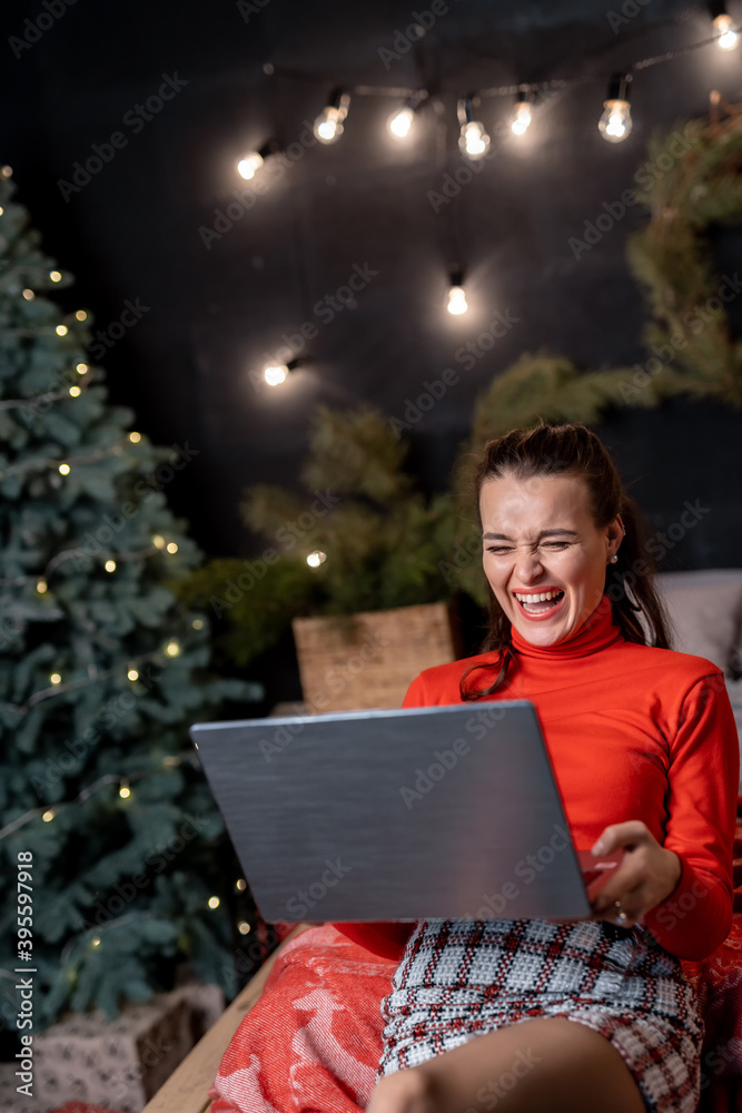 美丽的金发女子在圣诞节前用笔记本电脑和信用卡为家人购物