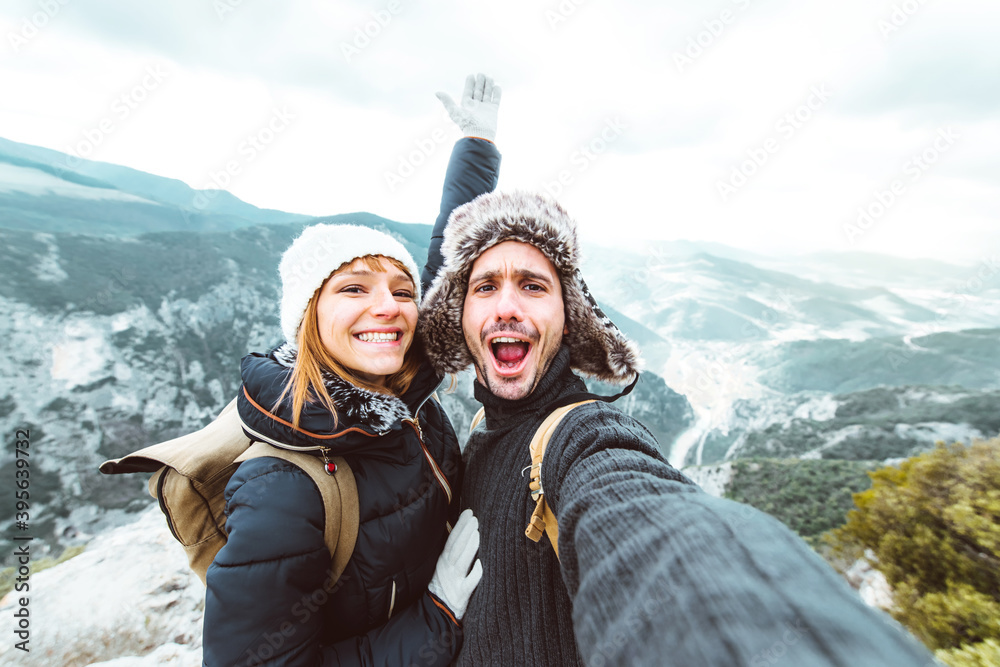 Happy couple taking a selfie hiking mountains - Successful hikers on the top of the peak smiling at 