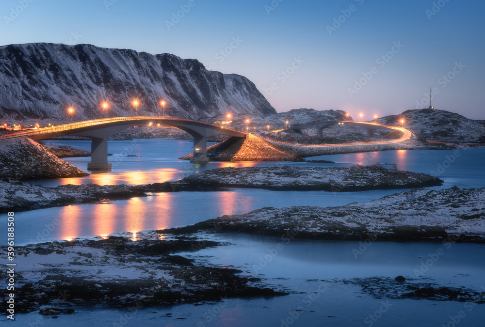 有照明的桥，白雪覆盖的山，村庄和蓝天，水中倒影。Nig