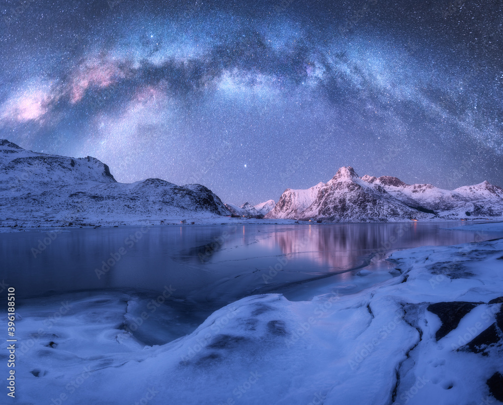 北方罗弗敦群岛冬季夜晚冰冻海岸和积雪覆盖的山脉上方的银河系