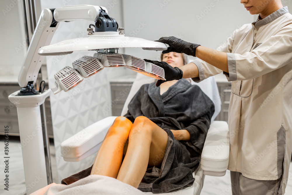 Woman doing led light therapy on her legs with a doctor at luxury medical office. Concept of a Heali