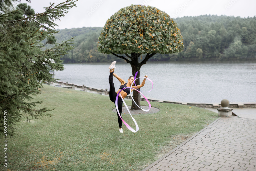 运动型女子在户外用缎带练习艺术体操