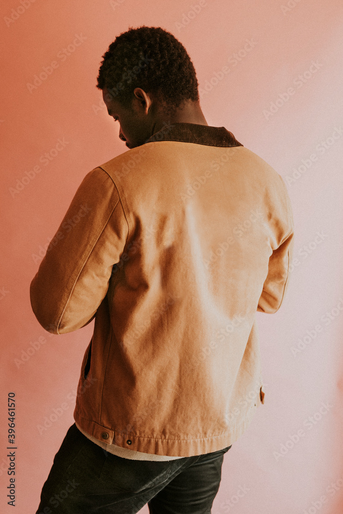 身穿棕色夹克的黑人模特在粉色背景下拍摄
