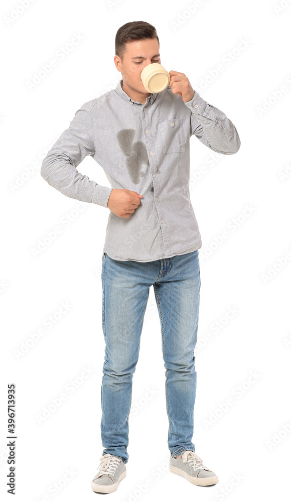 Young man with stains on his shirt drinks coffee on white background
