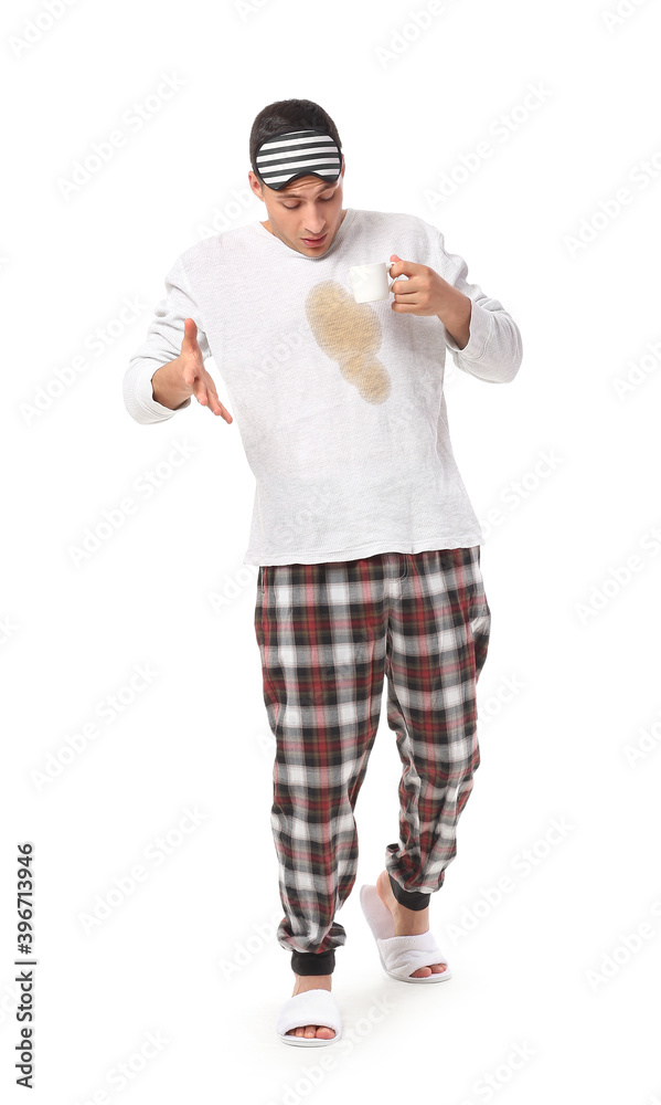 Stressed young man with coffee stains on his pajama top on white background