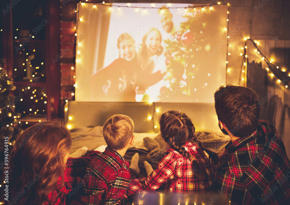 家庭母亲父亲和孩子在圣诞节晚上用爆米花看投影仪、电视、电影
