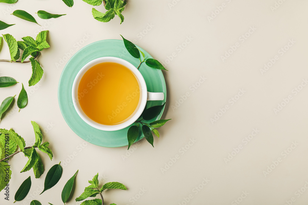 彩色背景上的一杯茶、薄荷和绿叶