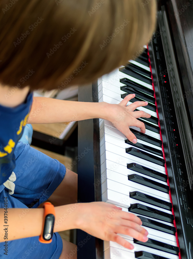 一个正在弹电子钢琴的无名高加索男孩的手。