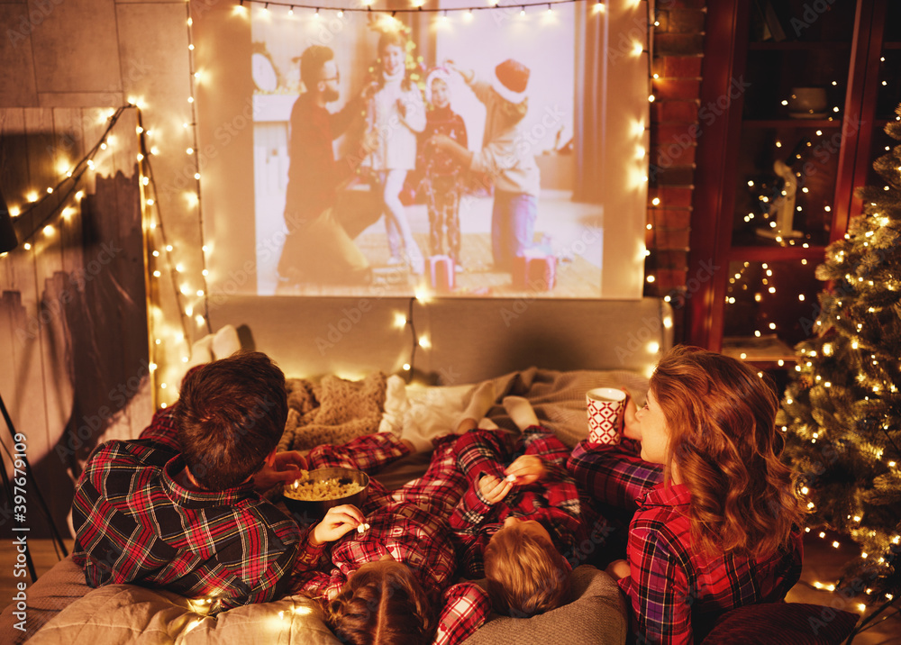 在圣诞夜，家庭母亲、父亲和孩子们用爆米花观看投影仪、电影和电影