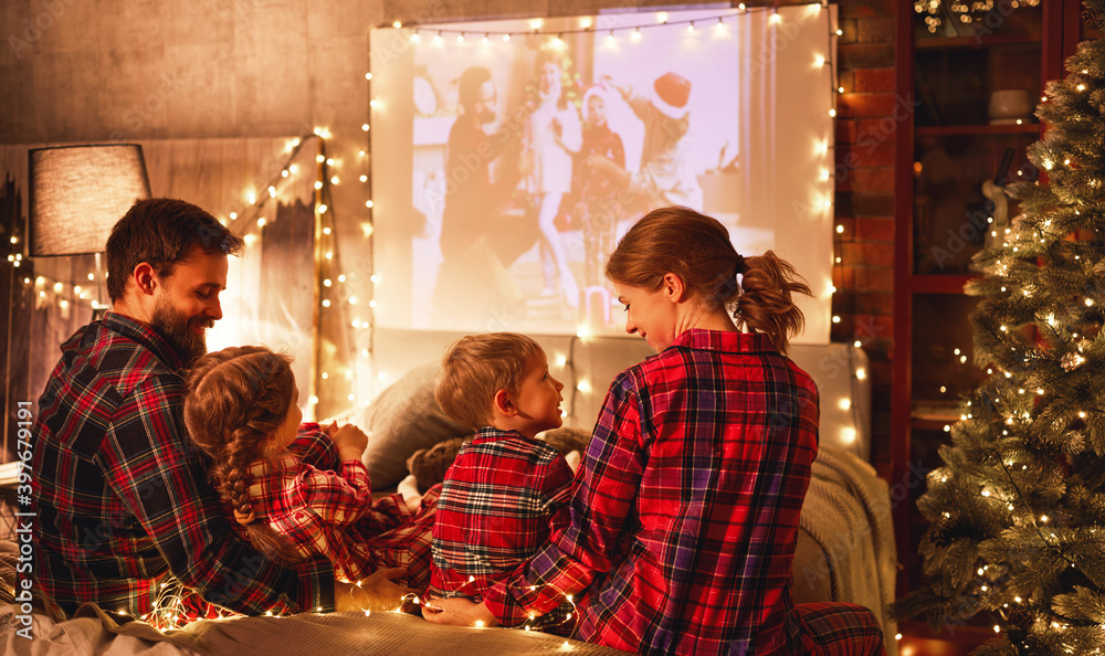 在圣诞夜，家庭妈妈、爸爸和孩子们用爆米花观看投影仪、电影和电影
