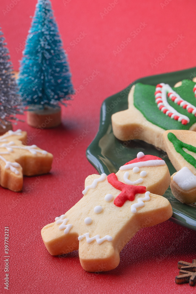 红色桌子背景的盘子里的圣诞糖饼干特写。