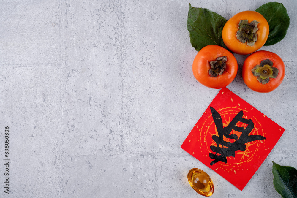 中国农历新年灰色餐桌背景上带叶子的新鲜甜柿子俯视图