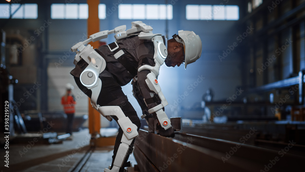 Black African American Engineer is Testing a Futuristic Bionic Exoskeleton and Picking Up Metal Obje