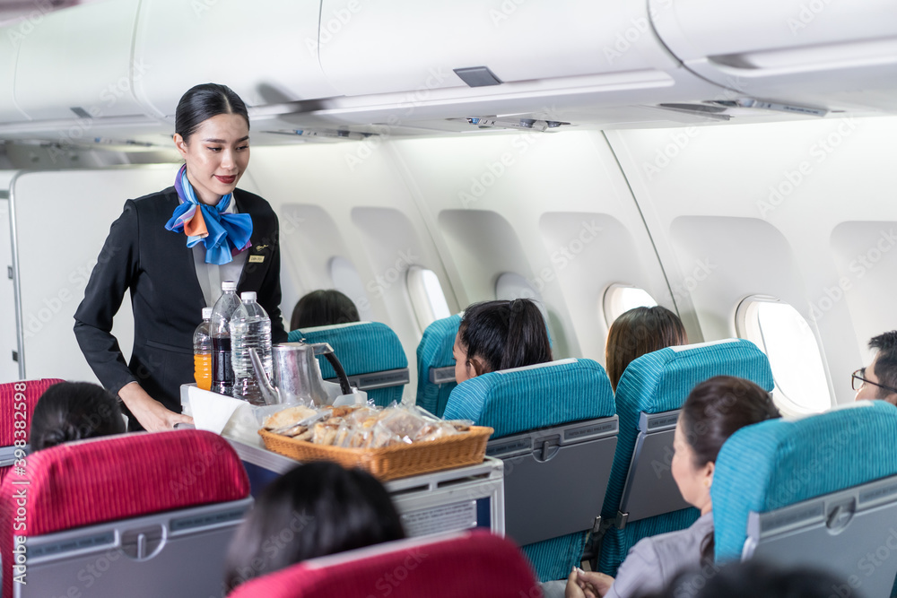 亚洲空乘人员在飞机上为乘客提供食物和饮料