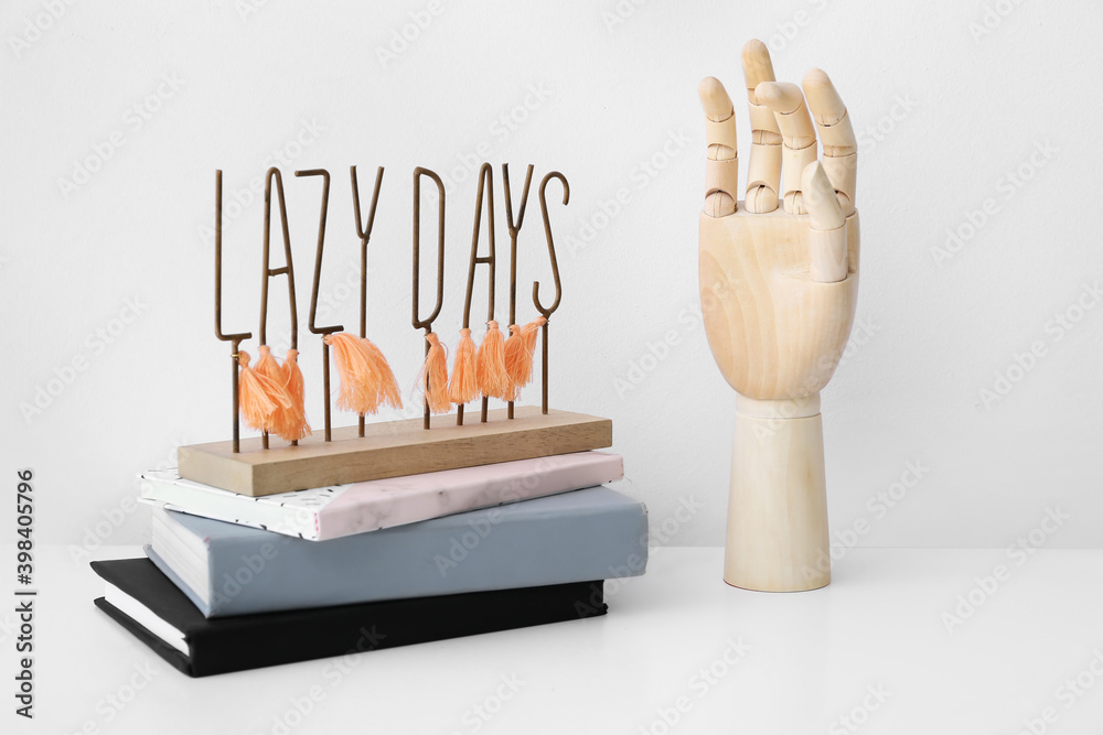 Wooden hand with books on light background