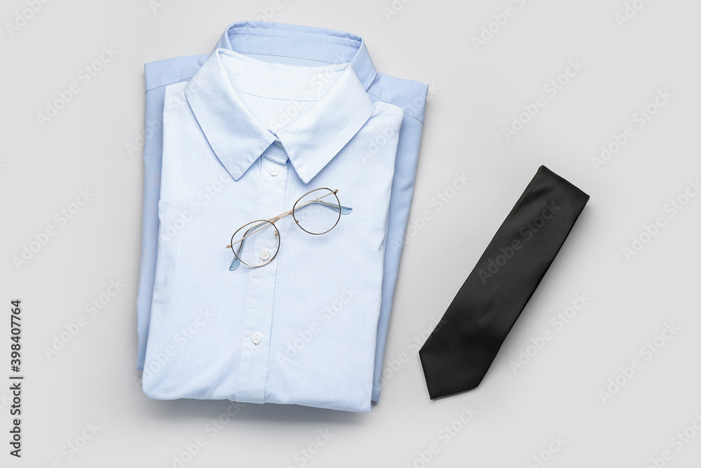 浅色背景的新款男士衬衫、眼镜和领带