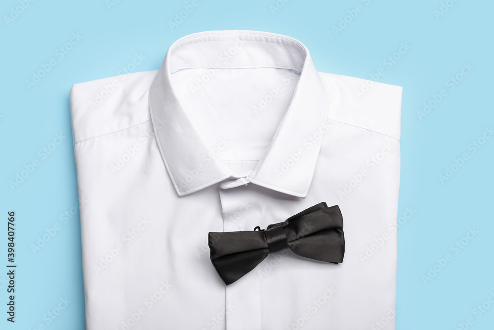 New male shirt and bow tie on color background