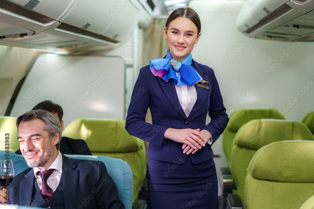 照片中一位身穿蓝色西装的年轻女子，飞机商务舱的空姐。