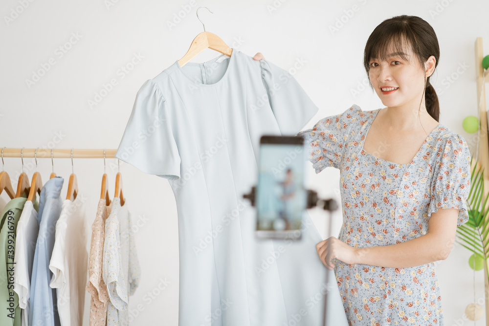 年轻的亚洲美女正在社交媒体上用智能手机直播卖衣服p