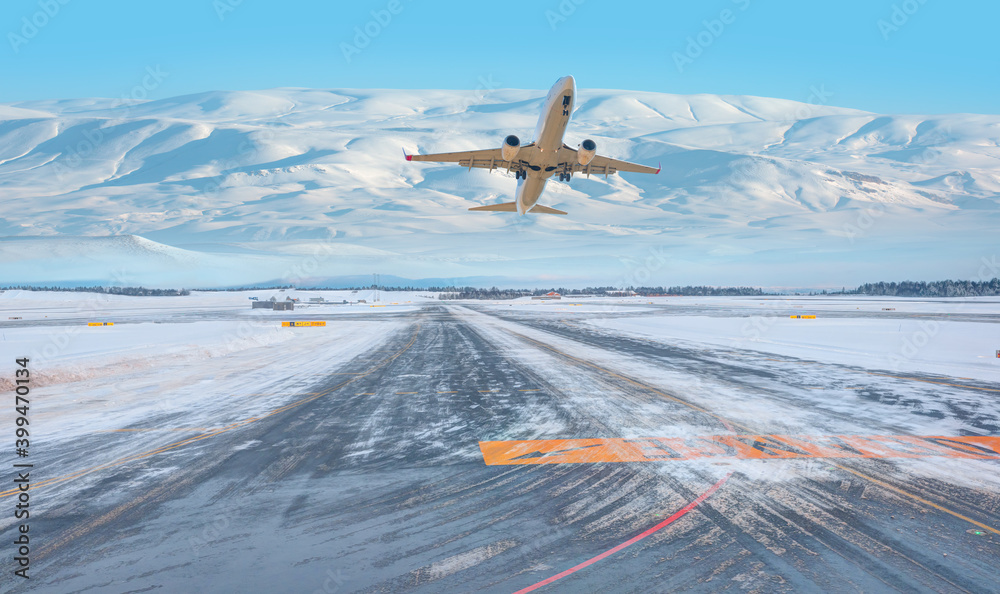 客机在起飞跑道上空飞过背景中的雪山-白雪覆盖的机场