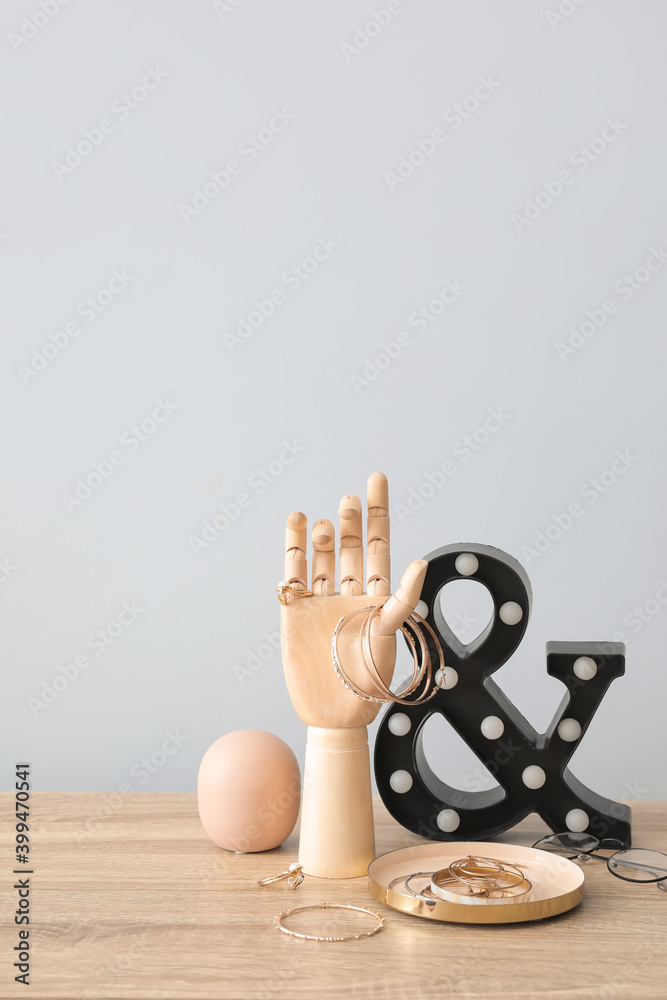 Wooden hand with female jewelry on table in interior of room