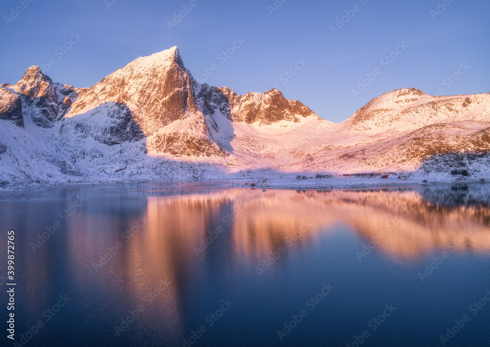 冬天日落时，美丽的雪山和蓝天映在水中。风景如画