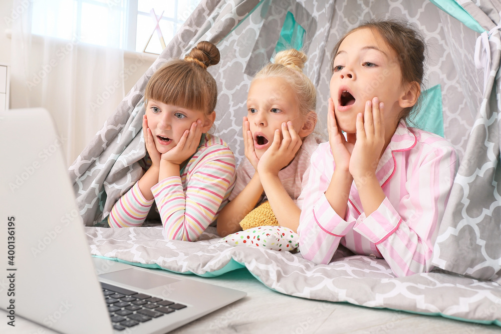 情绪激动的小女孩躺在棚屋里用笔记本电脑看电影