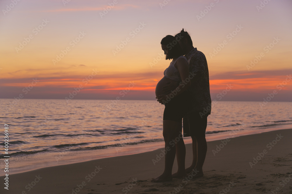 日落时分，年轻的家人和怀孕的妻子在海滩上度假。