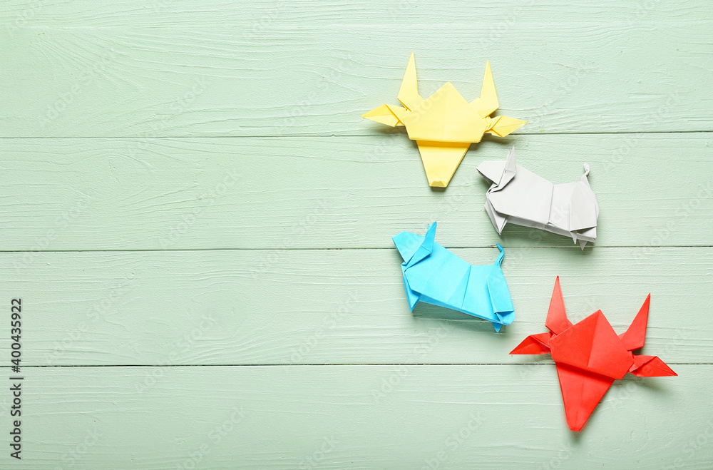 Origami bulls as symbol of year 2021 on color wooden background