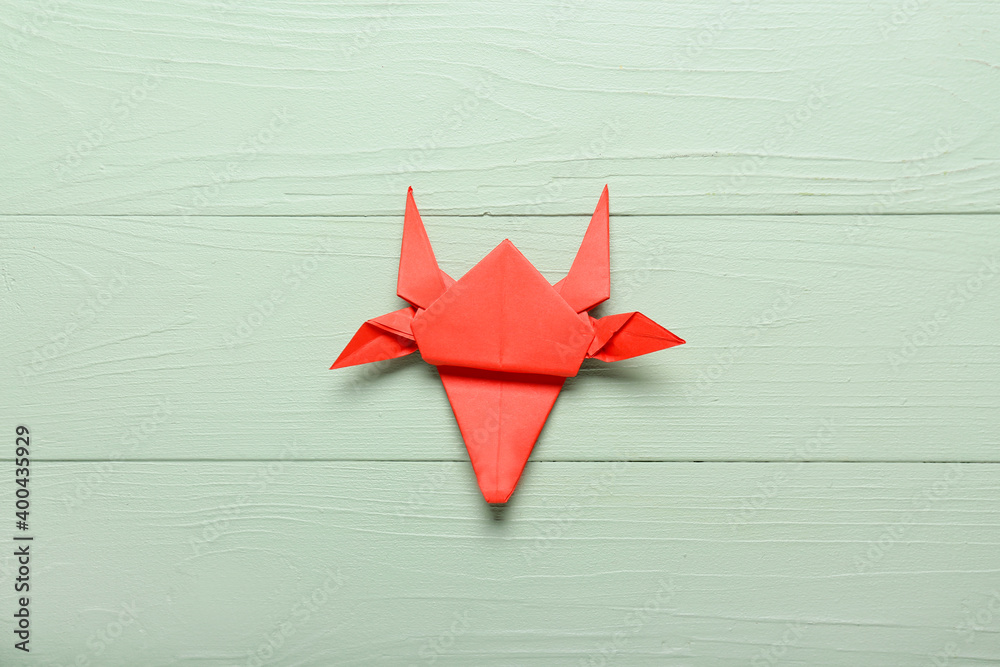 Origami bull as symbol of year 2021 on color wooden background