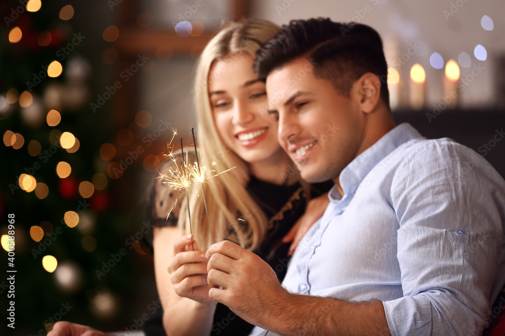 幸福的年轻夫妇在家里用焰火庆祝圣诞节