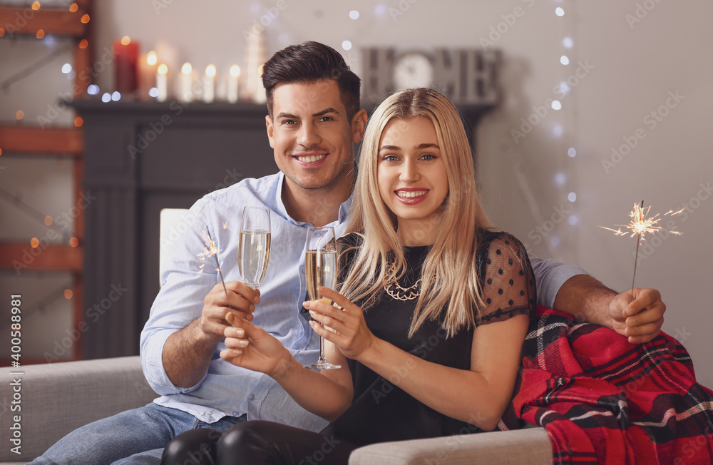 幸福的年轻夫妇，在家里用焰火和香槟庆祝圣诞节