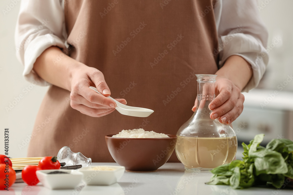 Woman preparing sauce with rice vinegar in kitchen