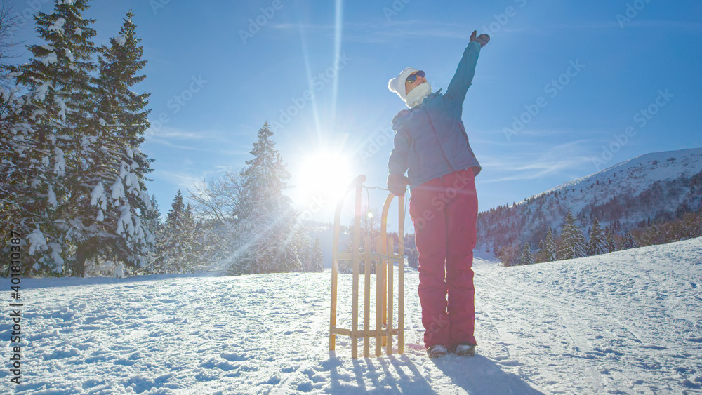 肖像：兴高采烈的女游客站在雪橇旁伸出手臂