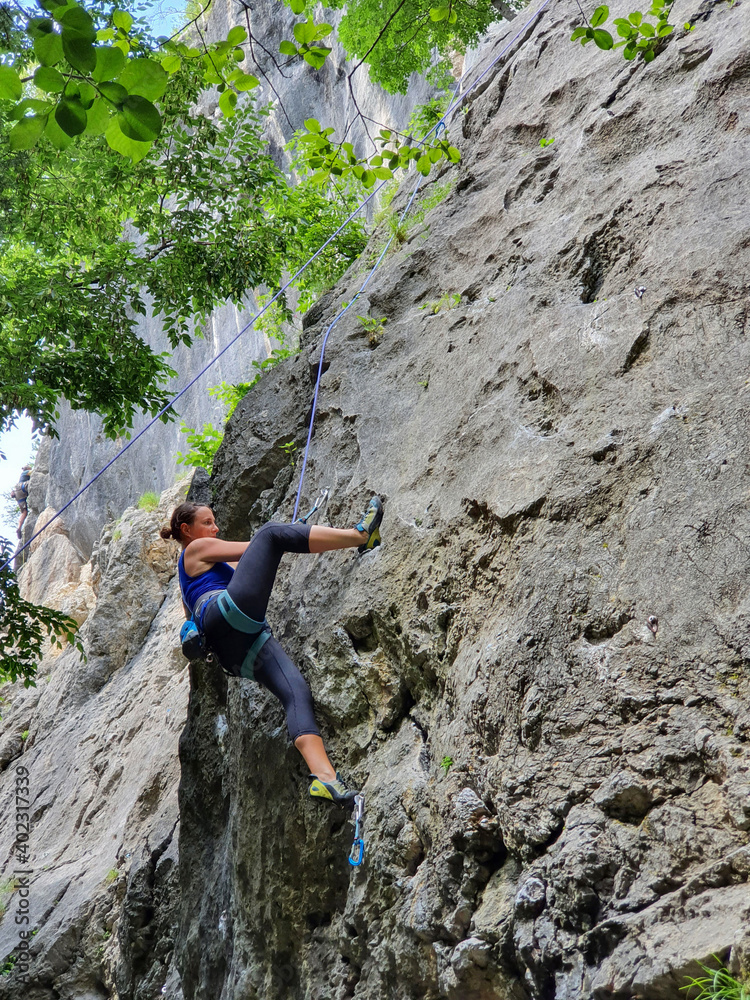 垂直：敏捷的高加索女性顶部绳索爬上高耸的岩壁。