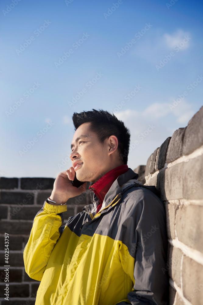 A young man use the mobile phone in the Great Wall Tourism 