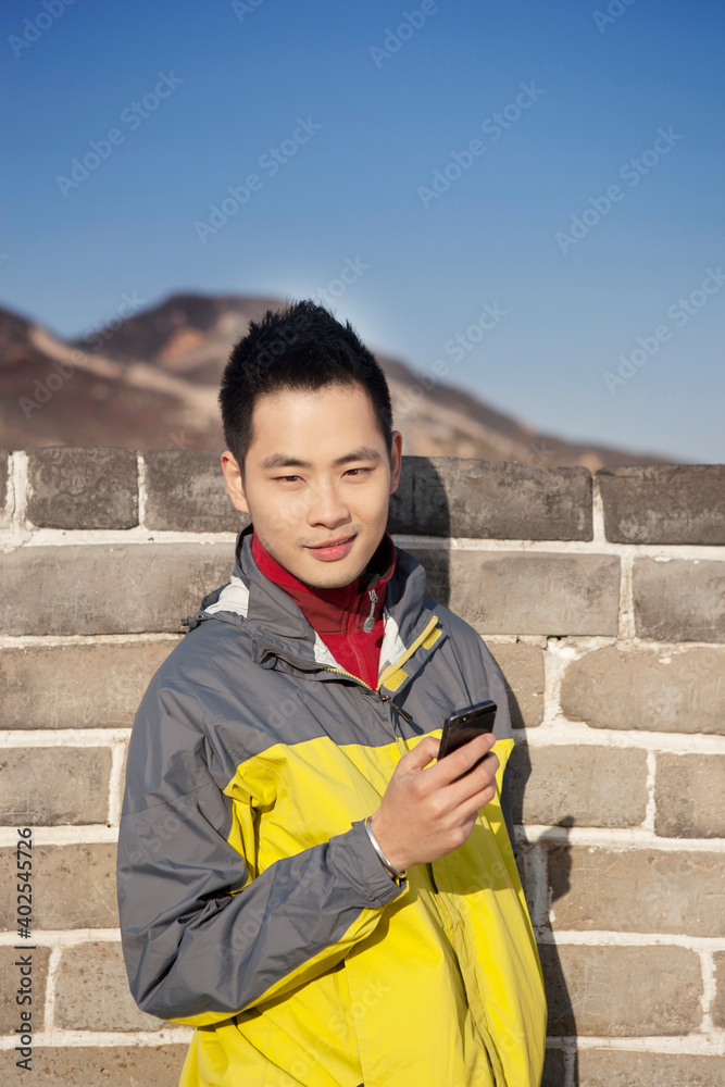 一个年轻人在长城旅游中使用手机