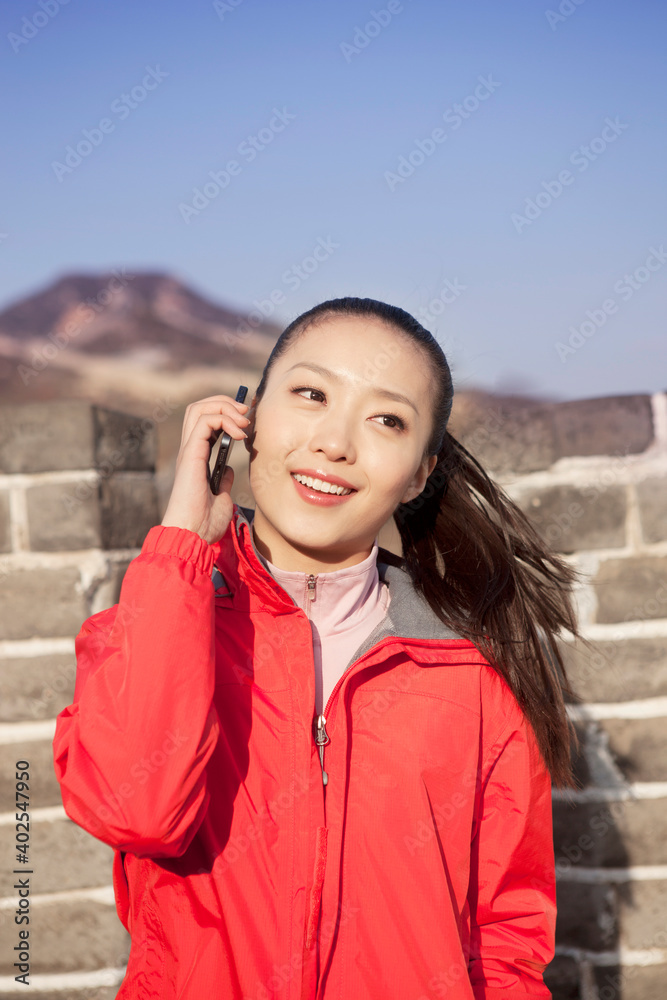 一名年轻女子在长城旅游中使用手机