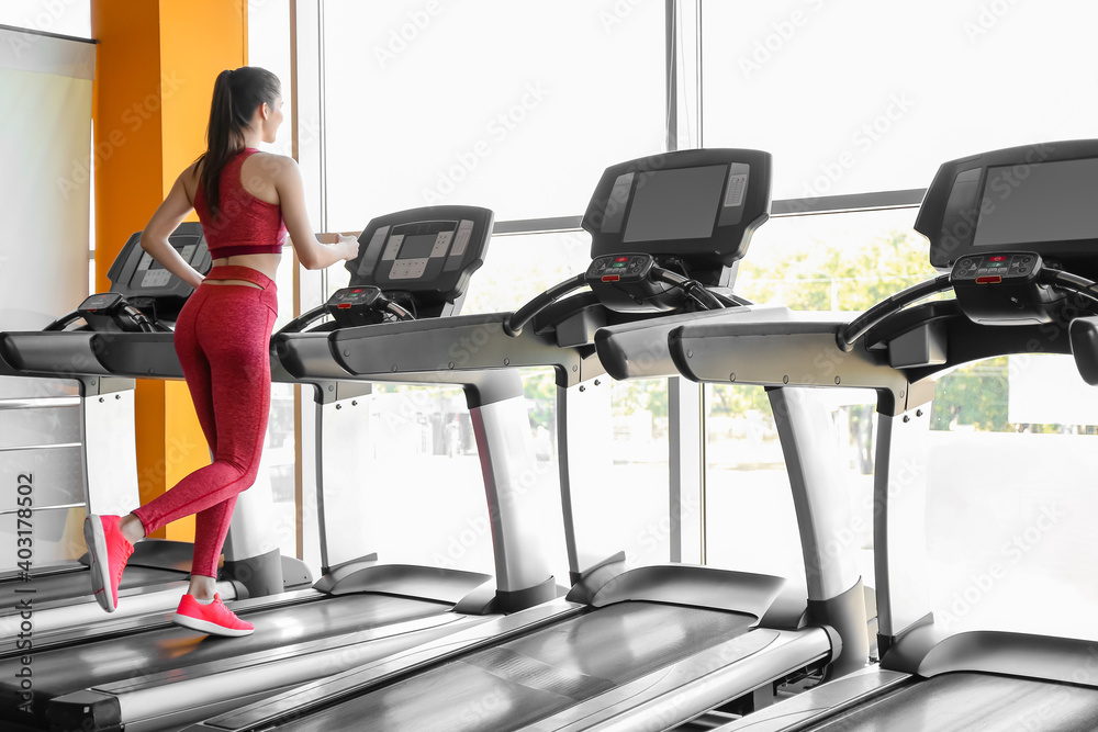 年轻女子在健身房跑步机上训练