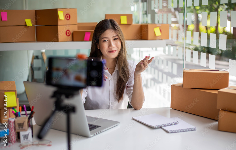 年轻的亚洲女企业家在家社交网络上用摄像机直播视频。在线