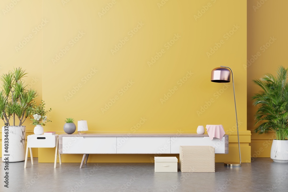 现代客厅的橱柜电视，黄色墙壁背景上有灯、桌子、花草。