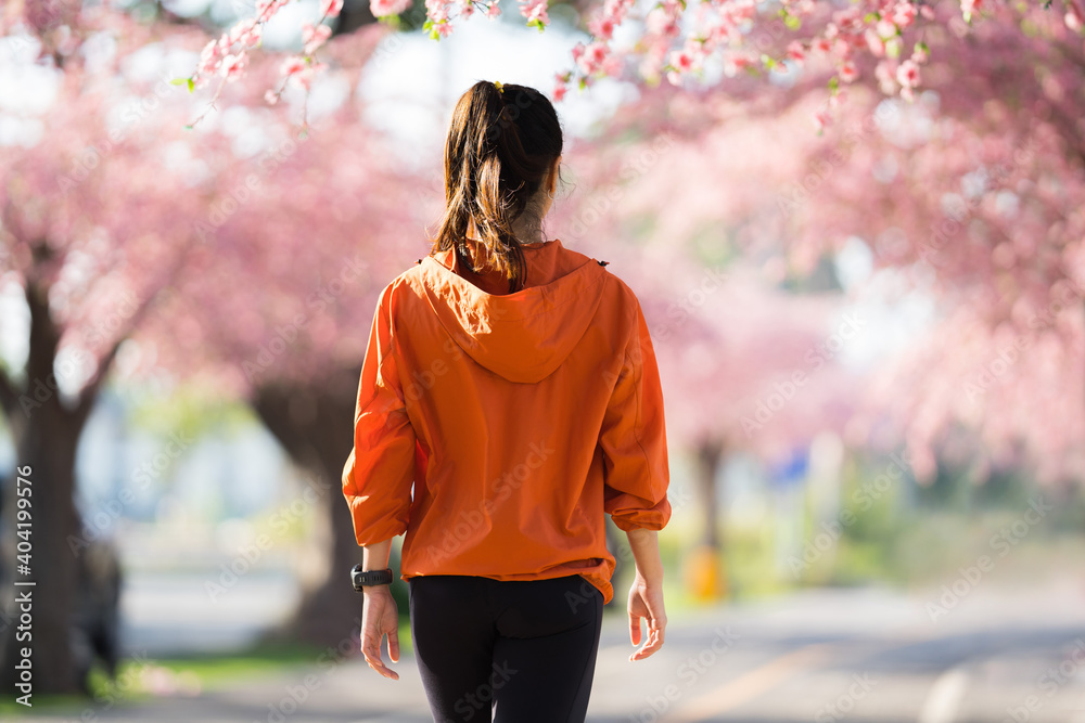亚洲女性早上锻炼她在樱花公园散步。