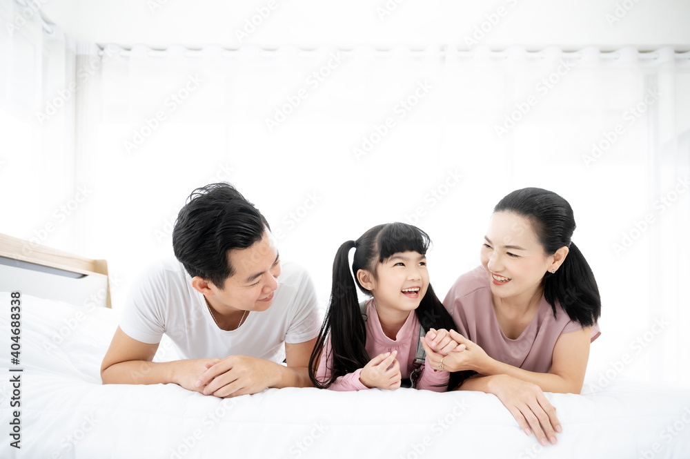 幸福的亚洲家庭人们一起在卧室里休闲。爸爸和妈妈带着女儿在b上放松