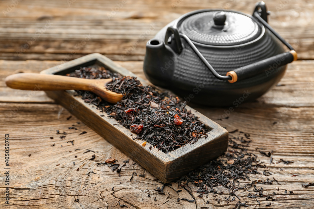 木制背景上有勺子和茶壶的盒子里的干红茶叶子