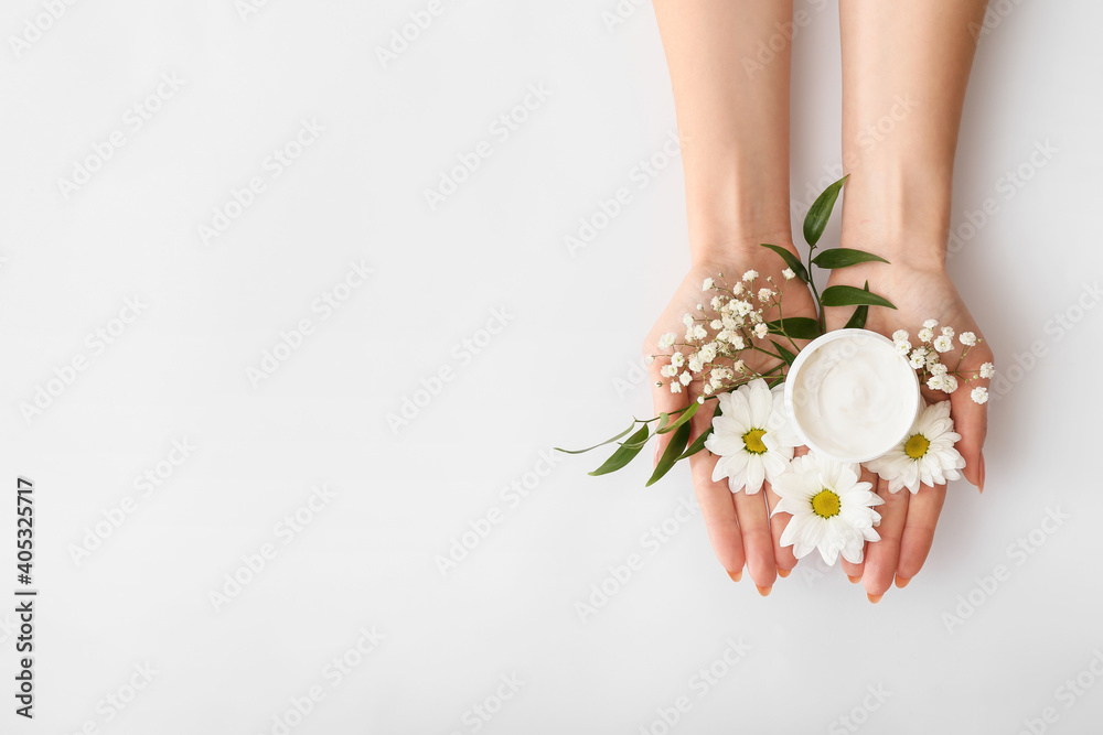 浅色背景上有奶油色和美丽花朵的女性双手