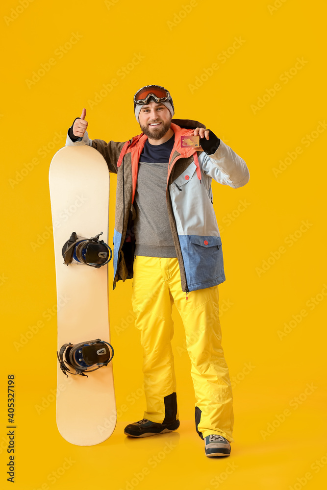 彩色背景上有信用卡的男单板滑雪运动员