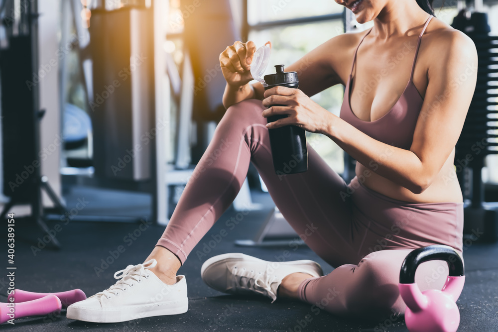 运动女性在健身中心锻炼，放松休息，美丽的女孩喝蛋白质